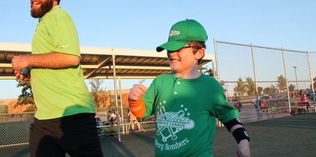 a PHS employee runs with a Miracle League MN baseball player