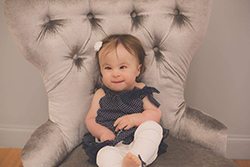 Addyson sits in a chair at 18 months
